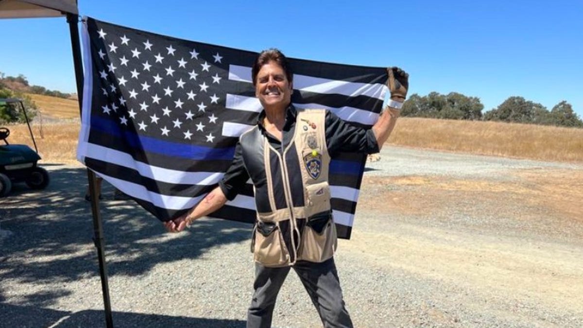 Erik Estrada poses with the blue flag on his back