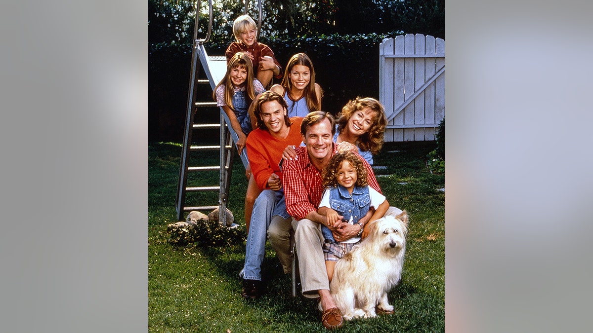 David Gallagher, Beverley Mitchell, Jessica Biel, Barry Watson, Stephen Collins, Catherine Hicks, MacKenzie Rosman, el perro Happy posan en lo alto de una escalera metálica