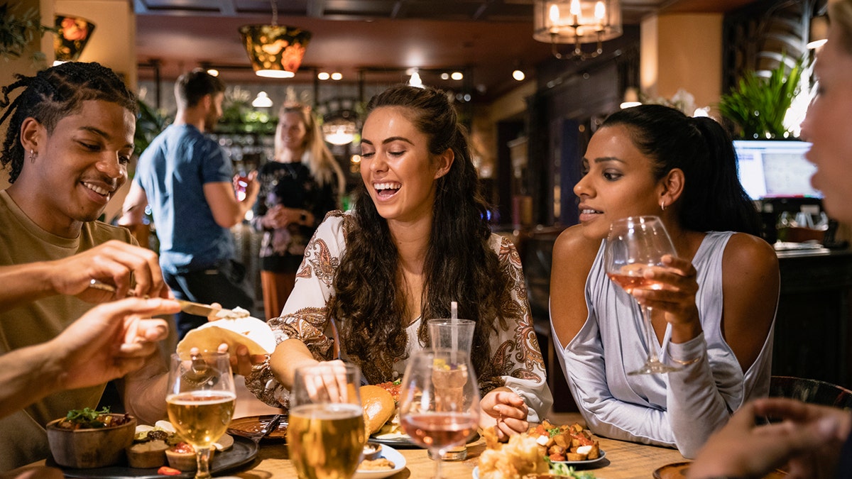 People laughing while eating dinner together