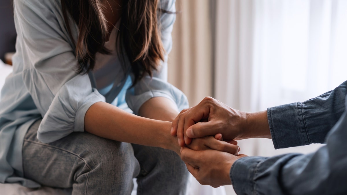 Two people holding hands in a comforting way