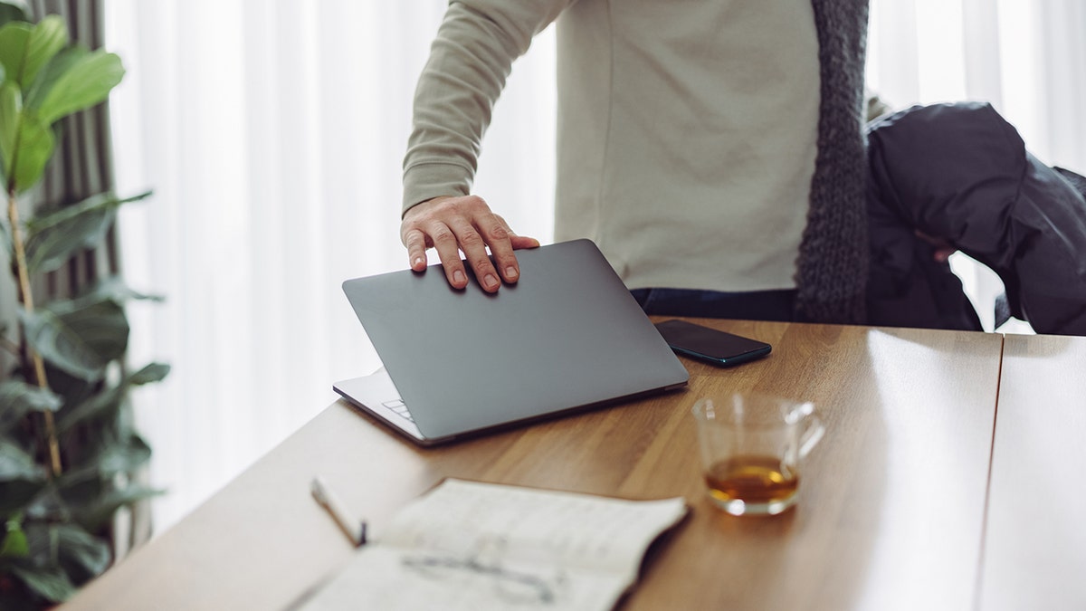 Close-up photo of a businessman closing his laptop 