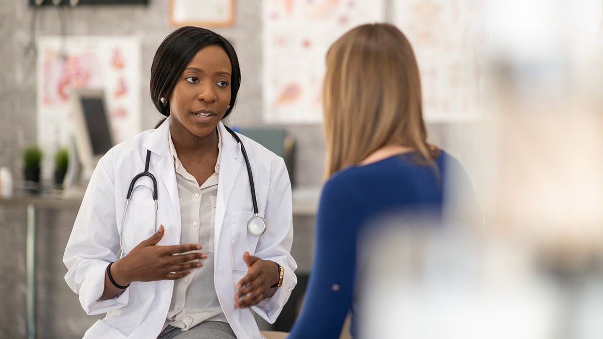 Una doctora se sienta frente a su paciente