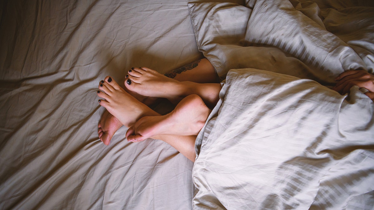 couple's feet intertwined in bed