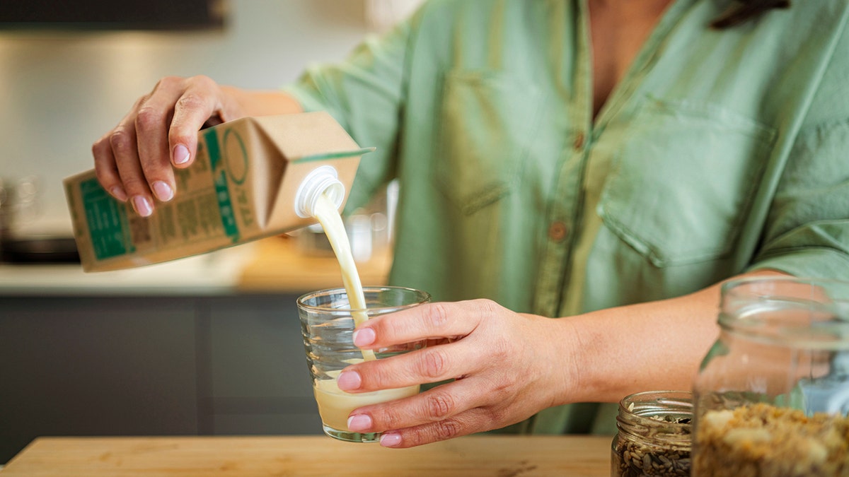 woman's hands pouring milk from a carton into a glass