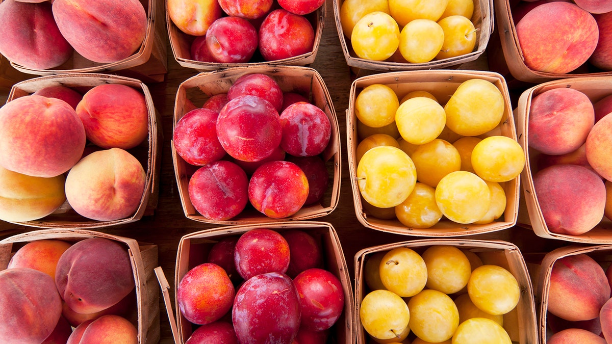 Ripe peaches and plums for sale at a farmers market in baskets.