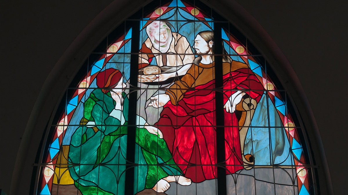 A stained glass window of Jesus, Mary, and Martha.