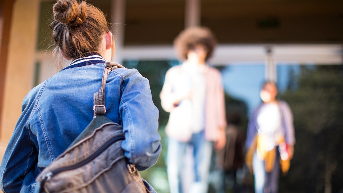 Young students connected  field  walking into building.