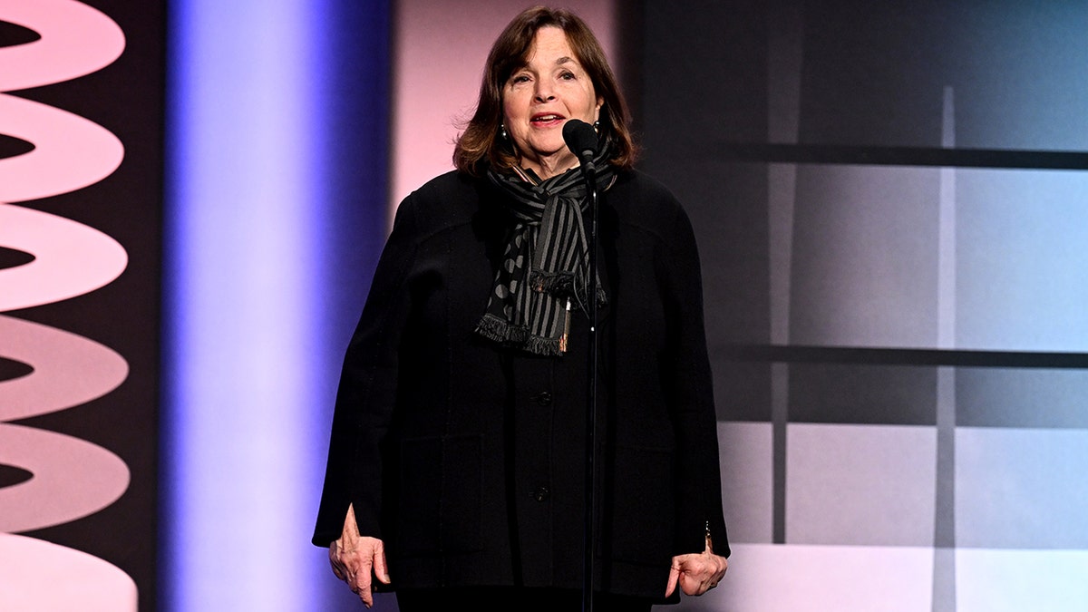 Ina Garten speaks on stage at the Webby Awards in a black outfit and a patterned black scarf