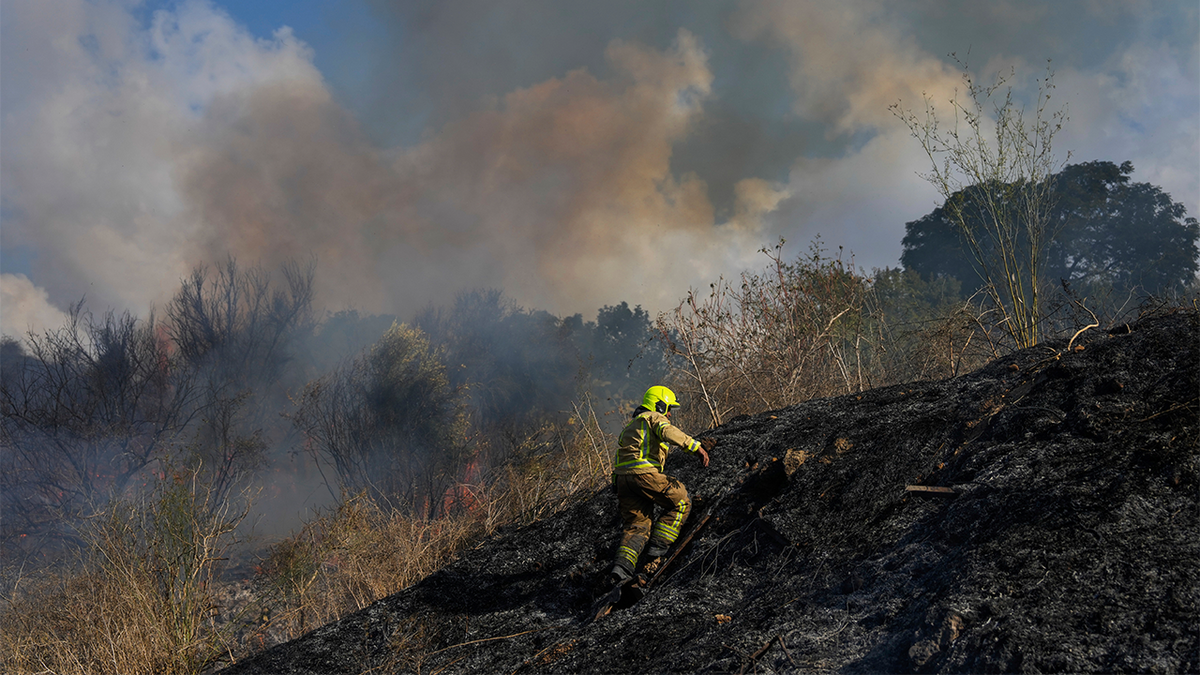 Un bombero trabaja en el área alrededor de un incendio.