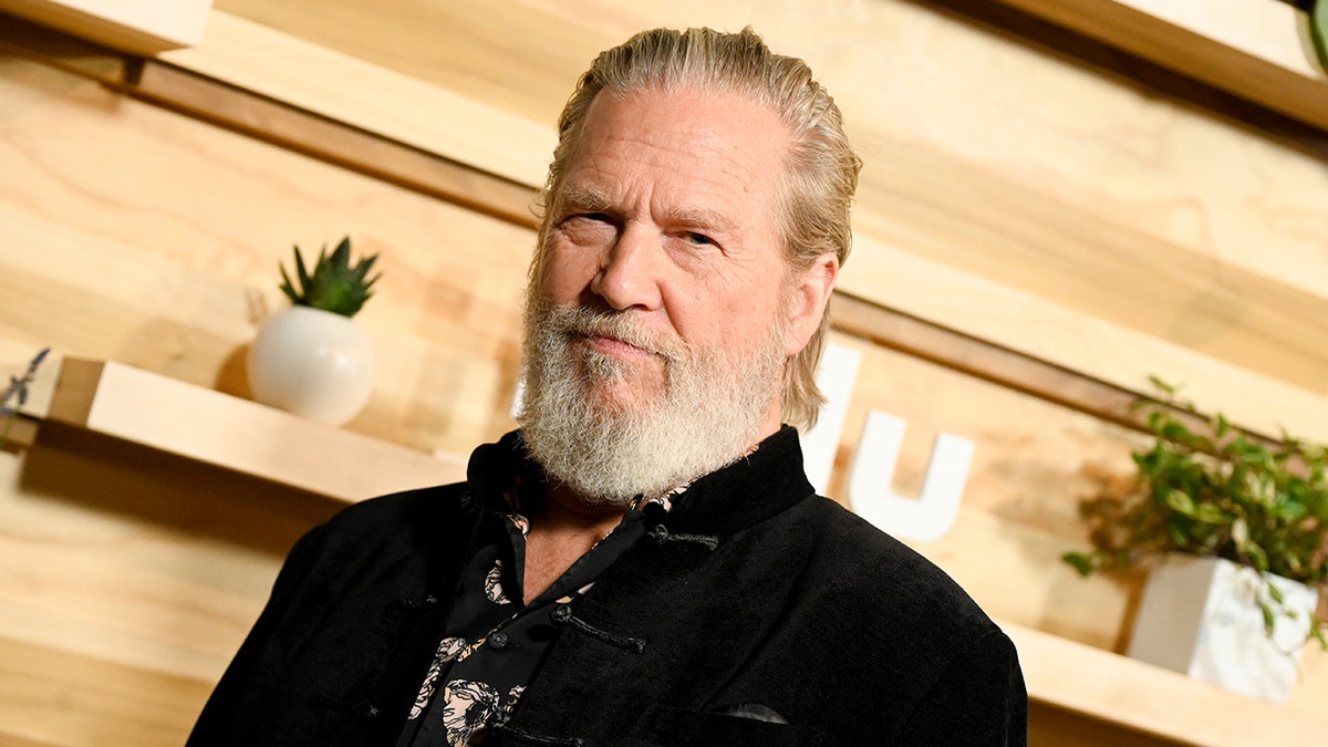 Jeff Bridges wears a achromatic  overgarment   connected  the reddish  carpet.