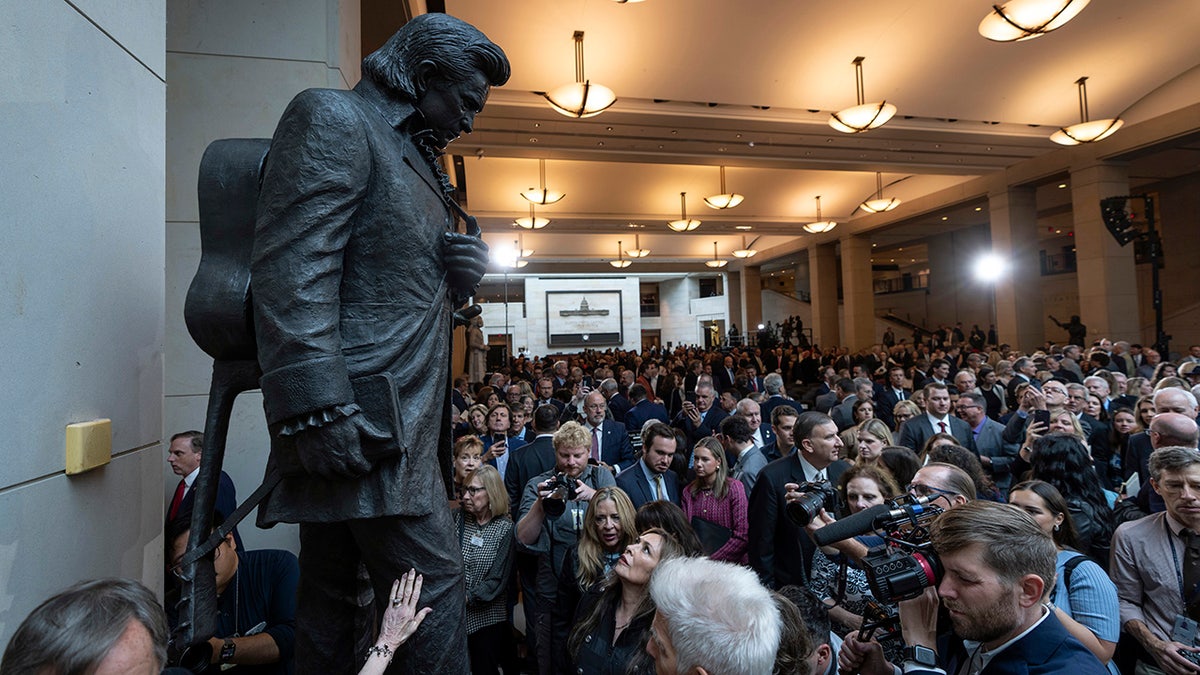 The statue depicts Cash holding a book  with his guitar slung crossed  his back.