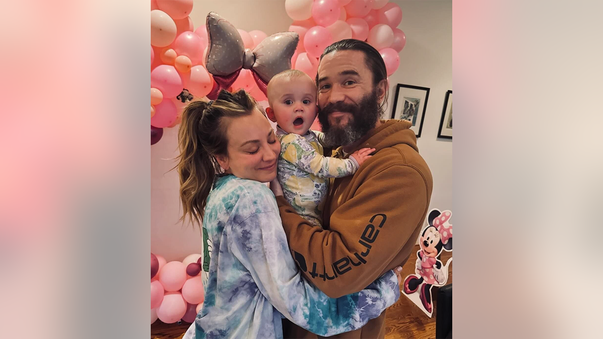 Kaley Cuoco con una camisa tie-dye abraza a su marido Tom Pelphrey con una sudadera naranja quemado sosteniendo a su hija Matilda