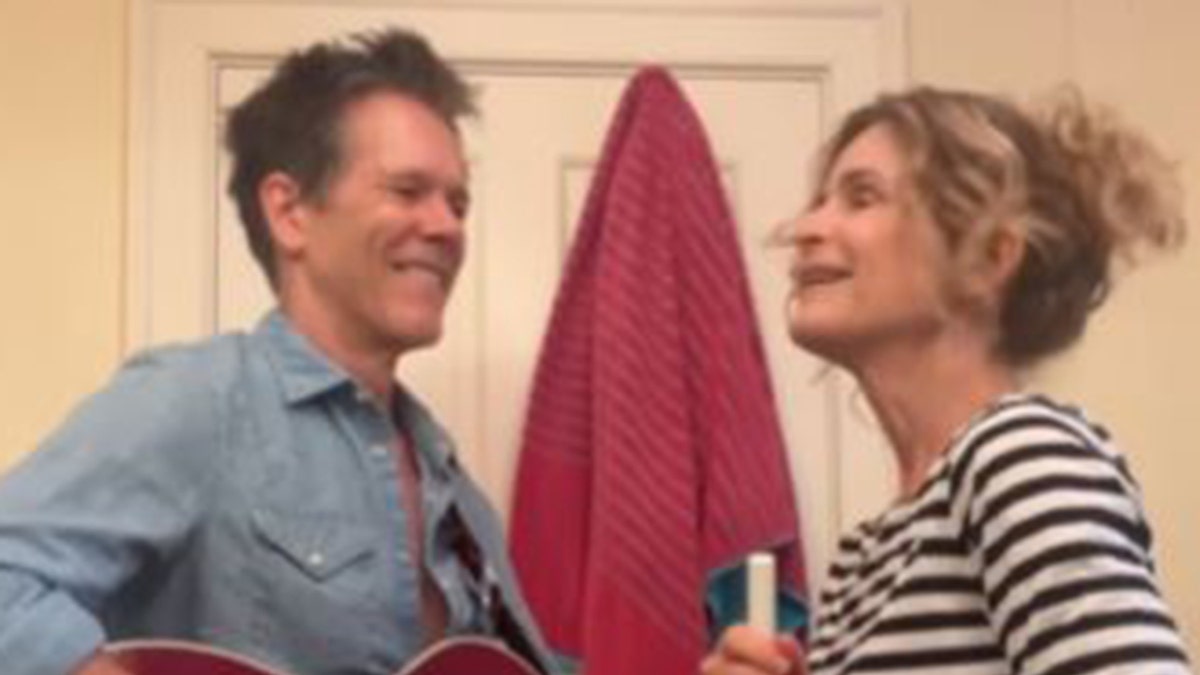 Kevin bacon holds a guitar while singing with wife Kyra Sedgwick.