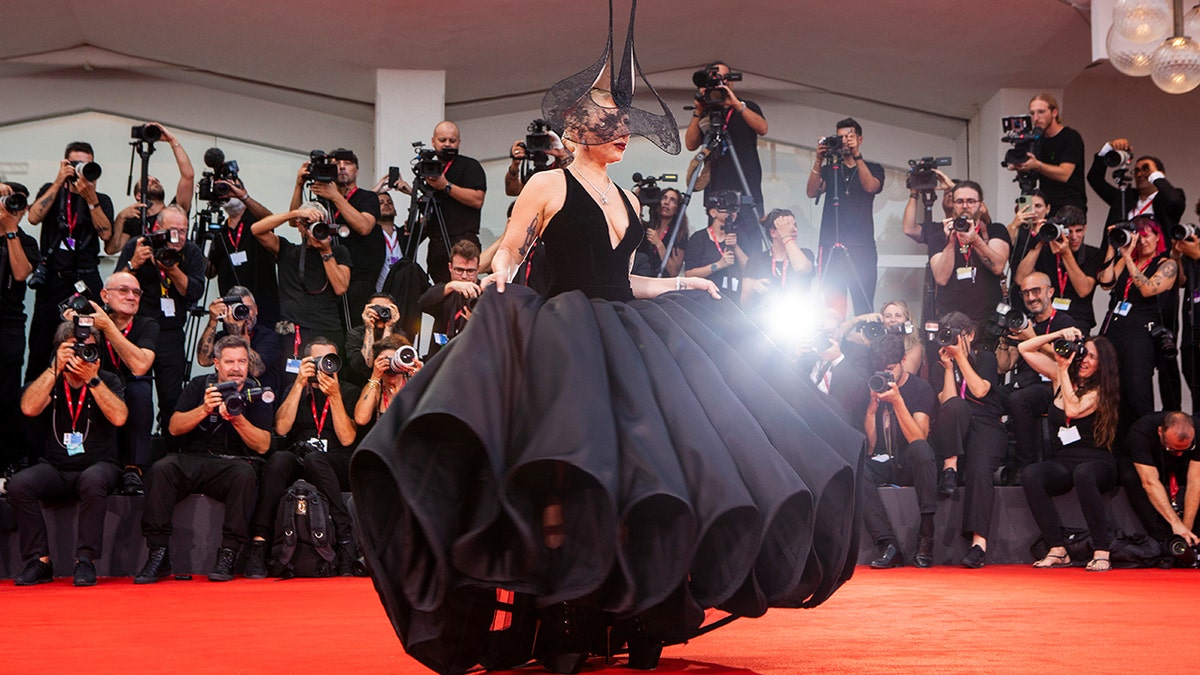 Lady Gaga poses in a black dress on the red carpet