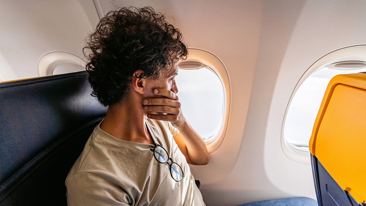 hombre tapándose la boca durante un vuelo