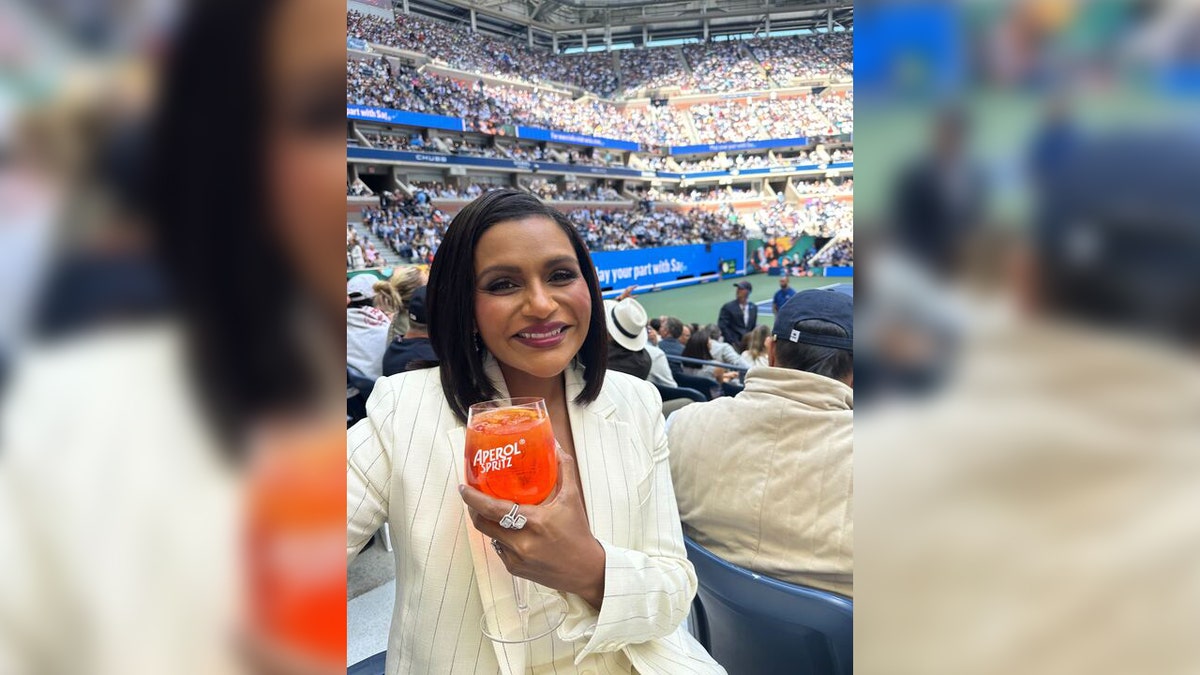 La actriz Mindy Kaling sostiene una bebida de naranja en el US Open.