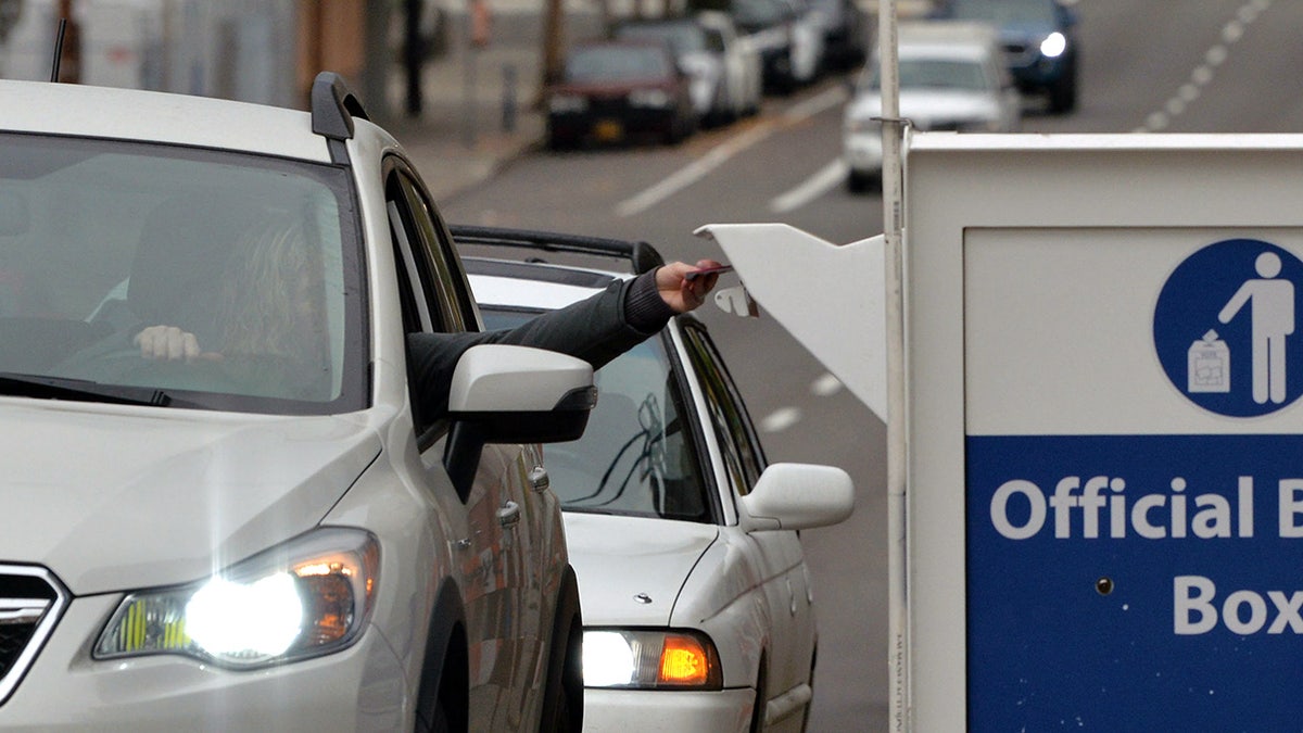 Un conductor deposita su papeleta en una urna de Oregón