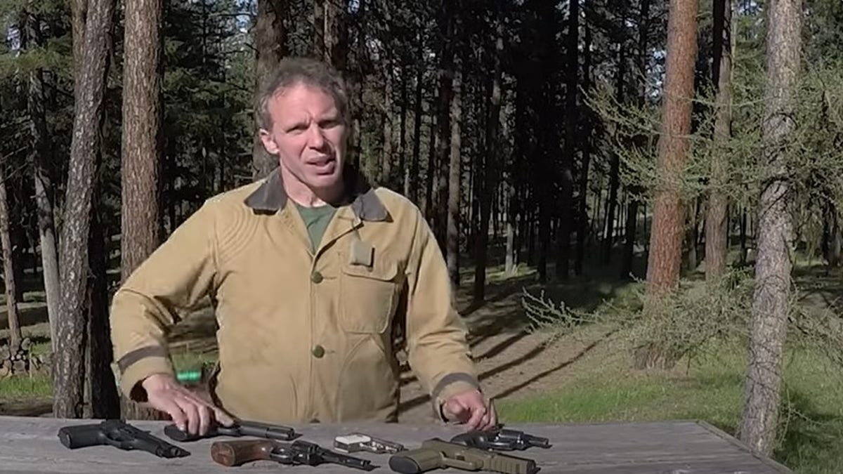 paul harrell em pé na frente de uma mesa de armas