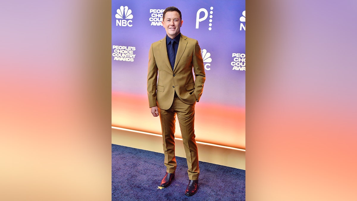 Scotty McCreery walked the red carpet at the 2024 People's Choice Country Awards in a brown suit.