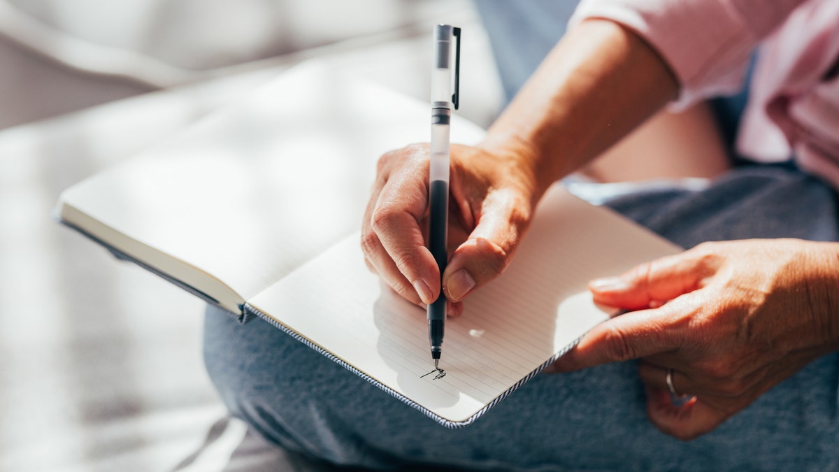 Una persona escribiendo en un diario 