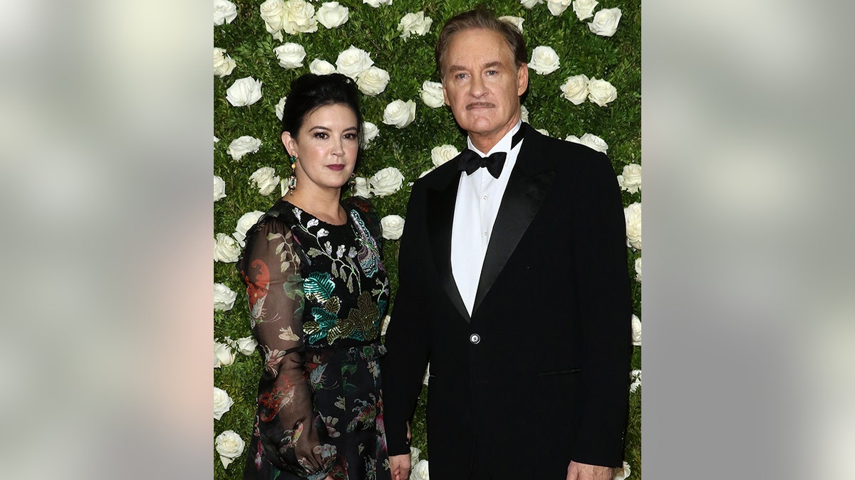 Phoebe Cates con un vestido negro estampado con mangas transparentes posa en la alfombra con su marido Kevin Kline con un esmoquin clásico