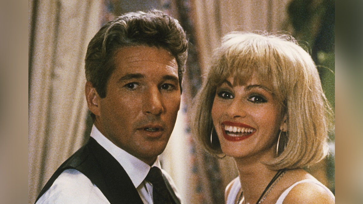 Richard Gere looks surprised as Julia Roberts in a short blonde bob smiles in character in "Pretty Woman"