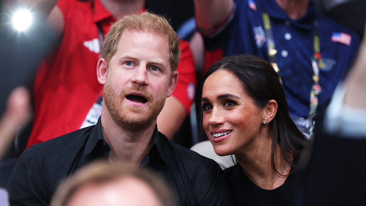 Prince Harry and Meghan Markle sit together in the audience