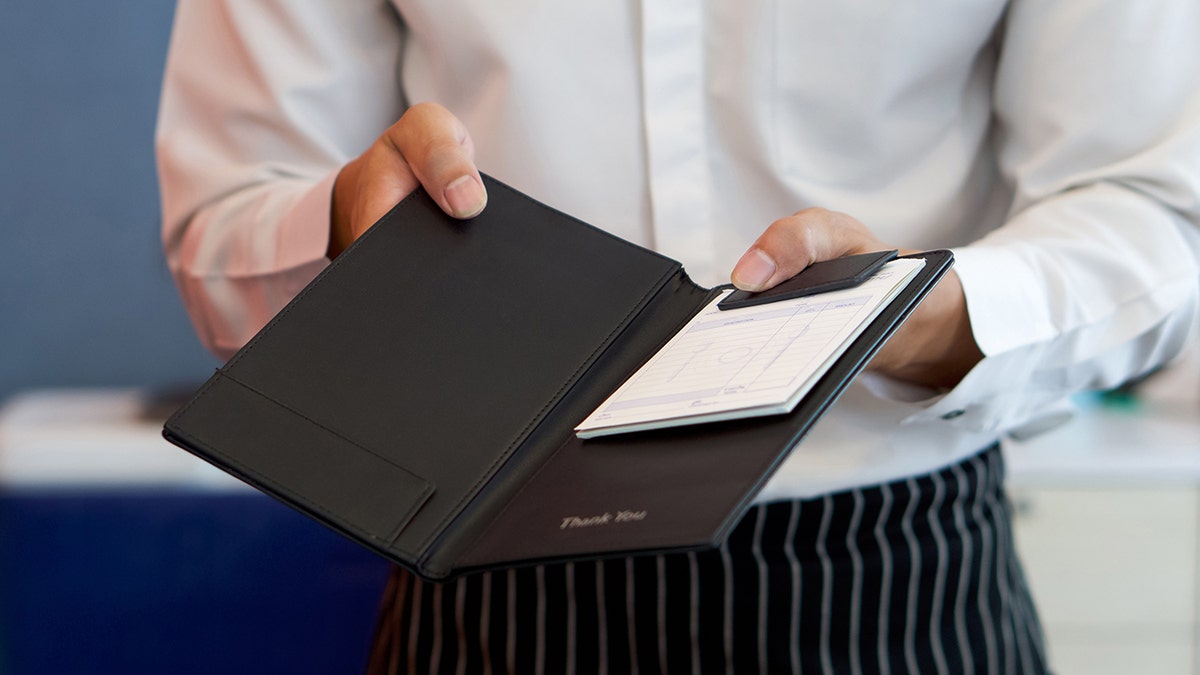 Waiter in restaurant with check