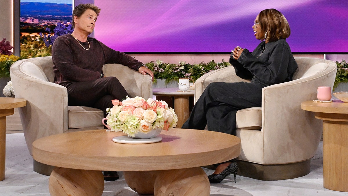 Rob Lowe sits on a chair and looks at Jennifer Hudson while on her talkshow