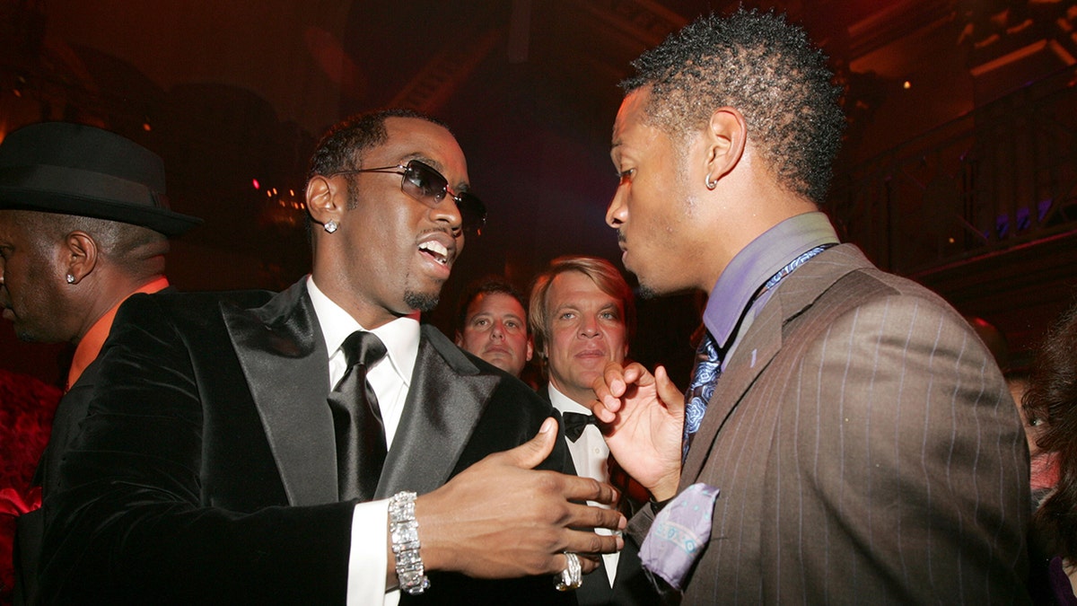 Sean 'Diddy' combs con traje negro y corbata habla con Marlon Wayans con traje marrón en un evento en NYC