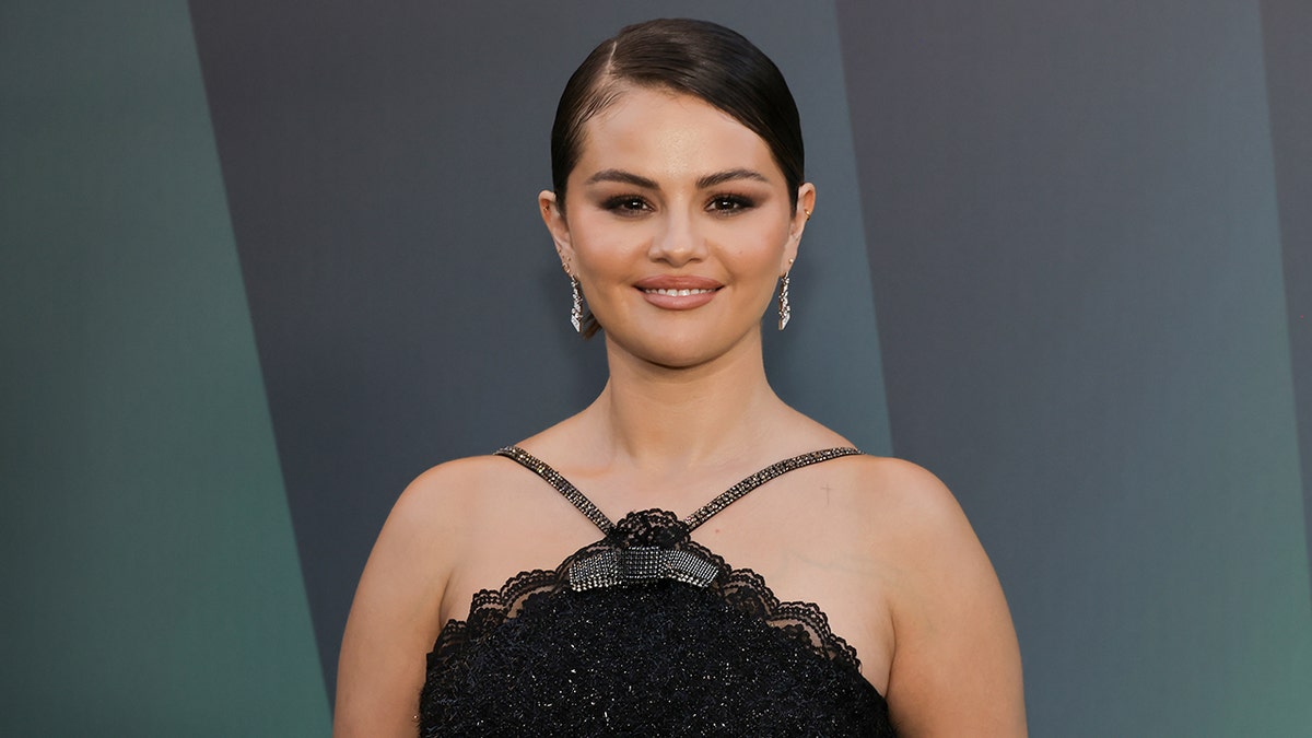 Selena Gomez smiles for the camera in a halter black lace dress on the carpet