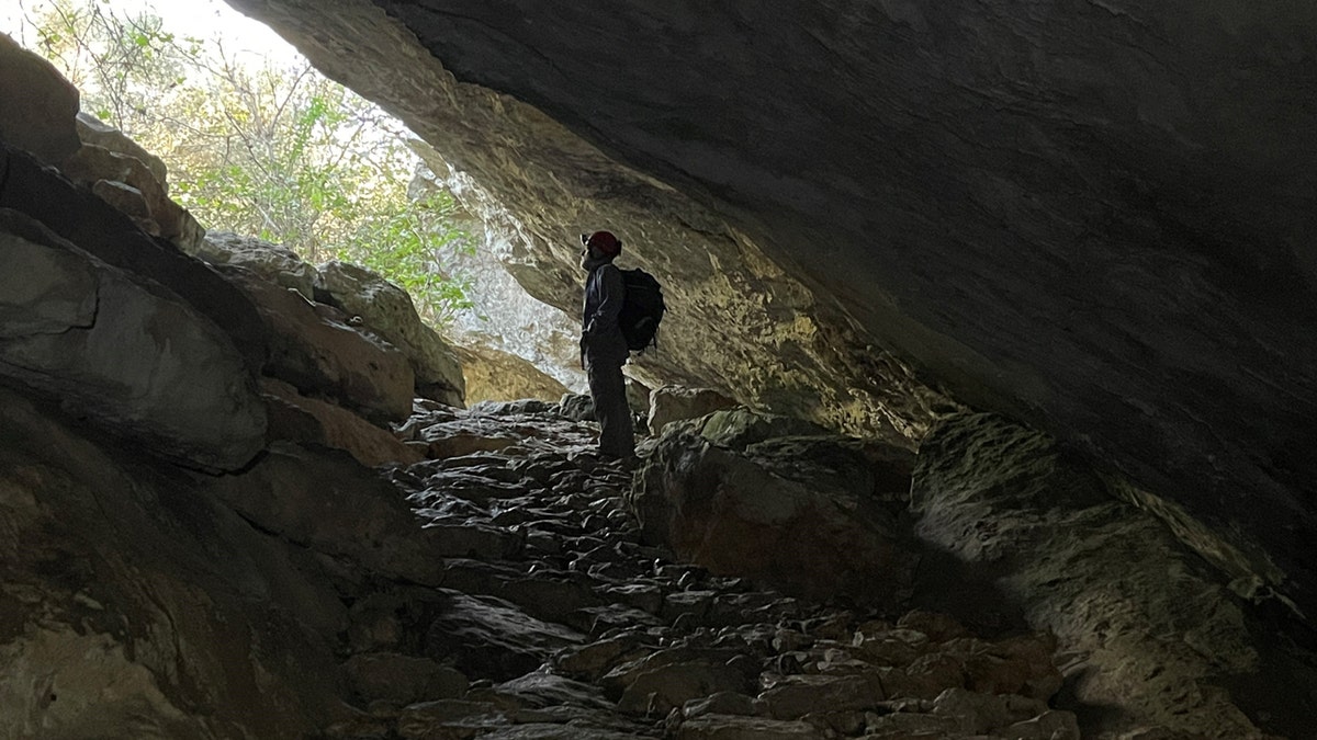 Un individuo de pie en la entrada de una cueva