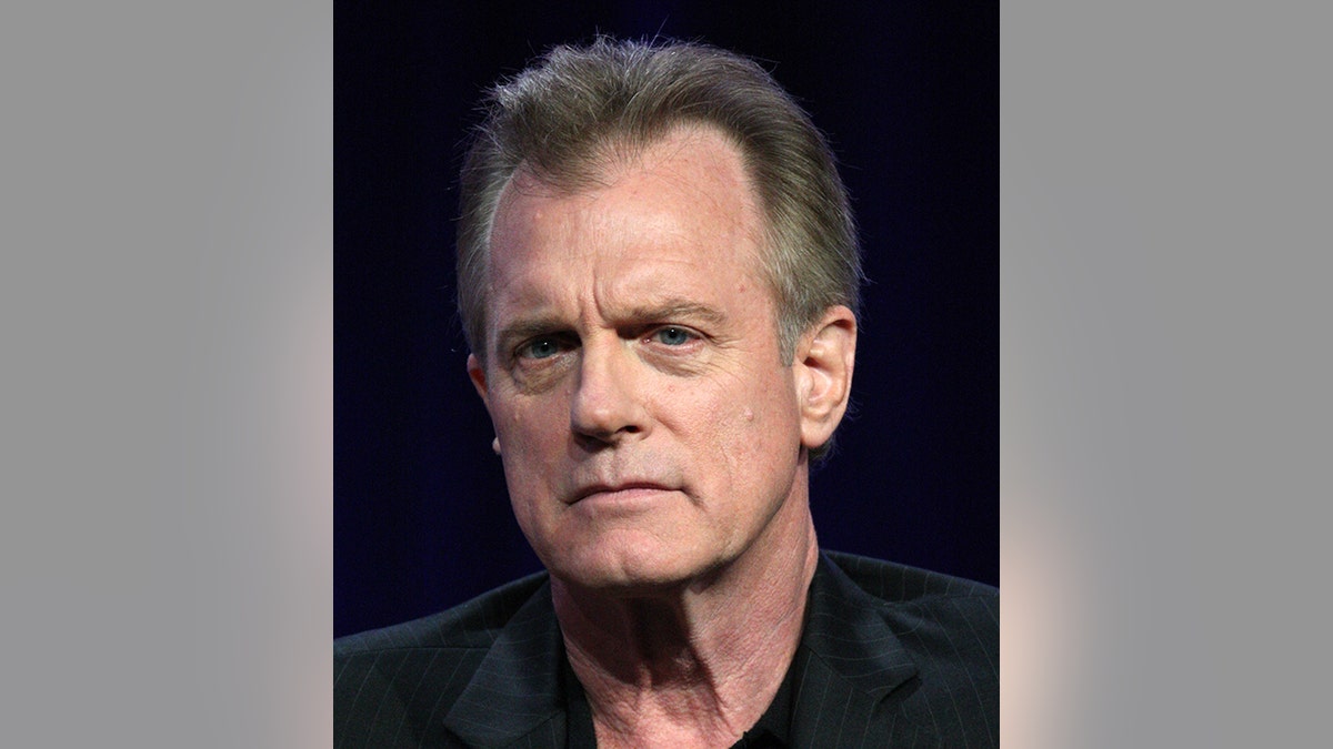 Stephen Collins in black shirt looks serious on stage 