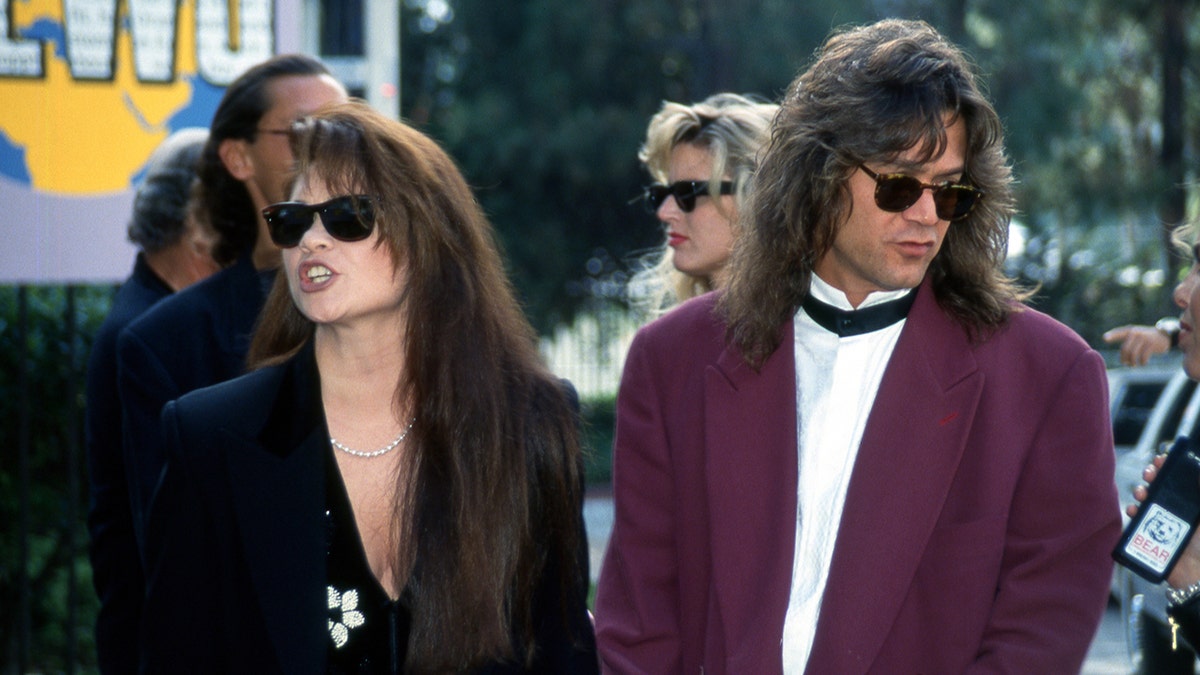 Valerie Bertinelli con americana negra y gafas de sol camina junto a Eddie Van Halen con chaqueta granate en los MTV Video Music Awards