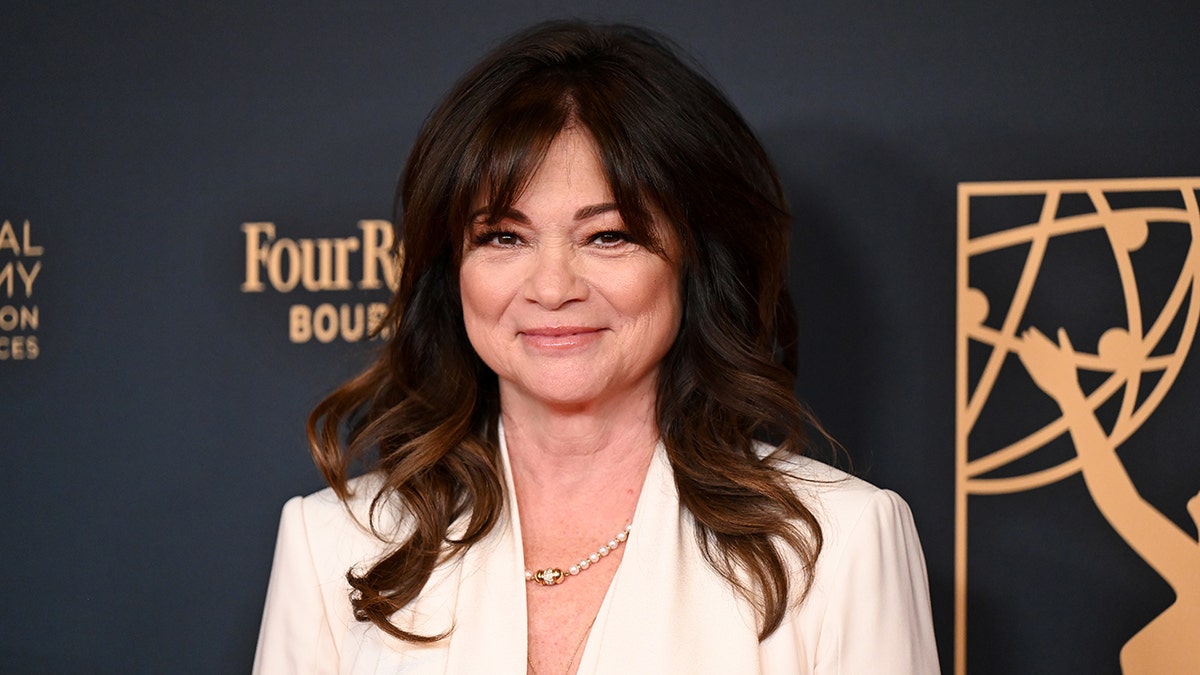 Valerie Bertinelli con un blazer blanco sonríe suavemente en la alfombra