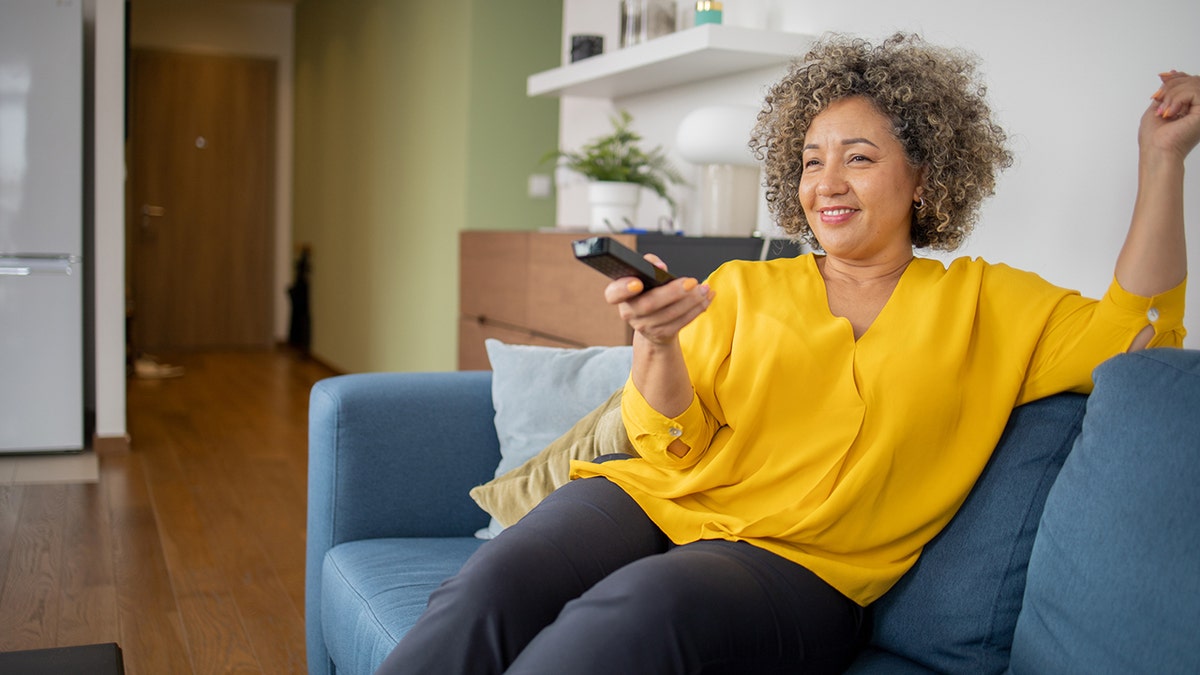 Mujer mayor sola viendo la tele en el sofá