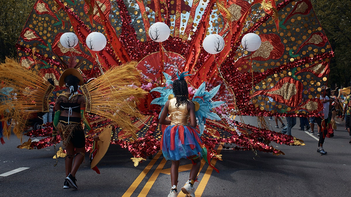 Parade members marching wearing colorful costumes.