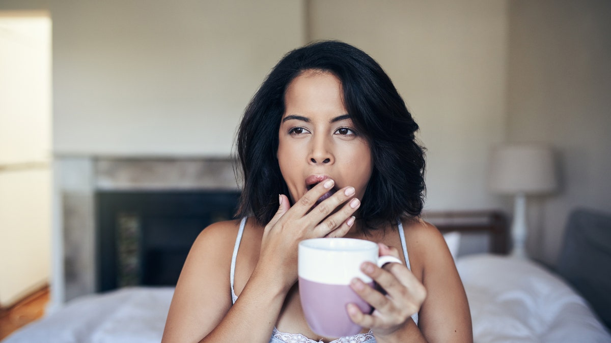 A woman waking up with a mug in her hand