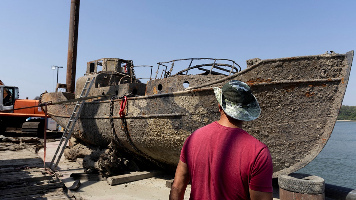 Un pescador inspecciona un buque de guerra alemán hundido de la Segunda Guerra Mundial, recuperado recientemente del río Danubio tras quedar expuesto debido a los bajos niveles de agua causados por la sequía y el calor extremo, en Prahovo.