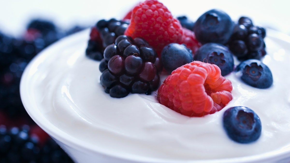 Fresas y arándanos sobre una taza de yogur.