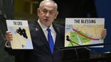 Prime Minister of Israel Benjamin Netanyahu hold signs as he addresses the 79th session of the United Nations General Assembly, Friday, Sept. 27, 2024. (AP Photo/Pamela Smith)