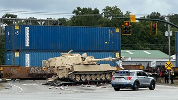 Train collides with military mobile artillery vehicle being hauled on a semi-truck