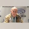 David Graham sitting during a panel wearing a tan jacket