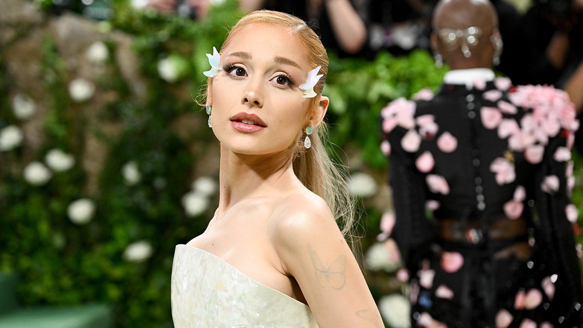 Ariana Grande in a strapless dress looks up and into the distance on the MET GALA carpet