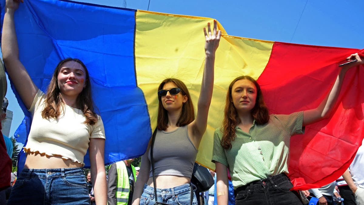 Women hold a Moldovan flag during a rally