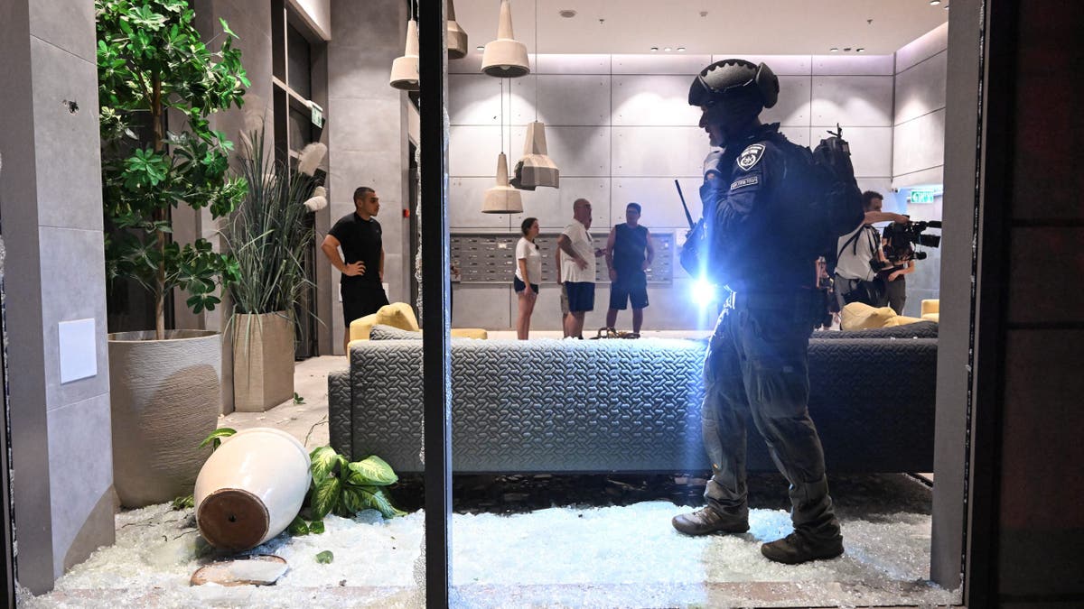 An Israeli police officer inspects the damage to a residential building caused by a rocket fired towards Israel from Lebanon, amid cross-border hostilities between Hezbollah and Israel, in Haifa, Israel, on Oct. 7, 2024.