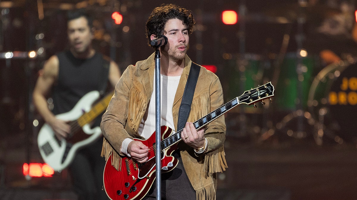 Nick Jonas playing guitar on stage