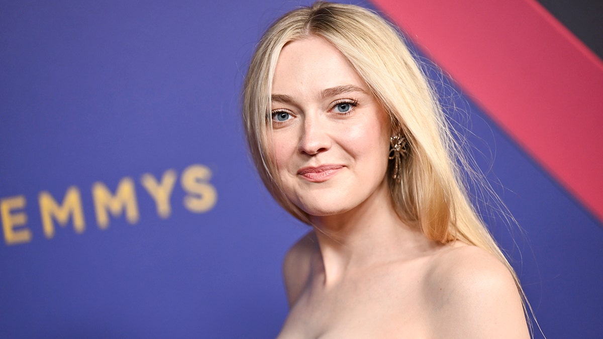 Dakota Fanning sorri suavemente no tapete do Emmy com o cabelo caindo sobre o ombro