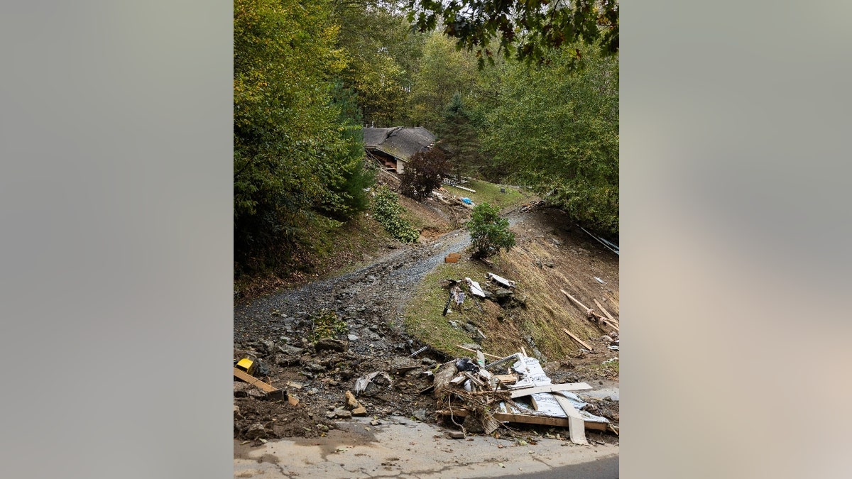 Uma casa destruída encosta em uma estrada íngreme de cascalho