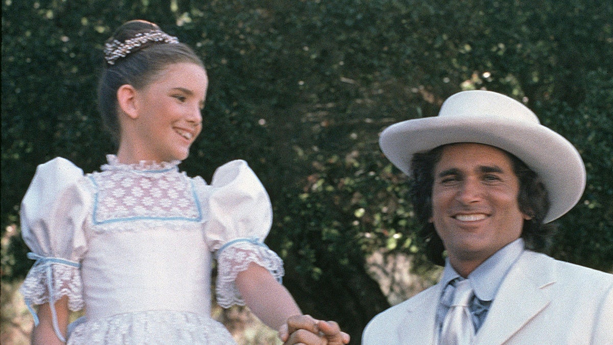 Melissa Gilbert wearing a white dress smiling at her TV dad Michael Landon also wearing white